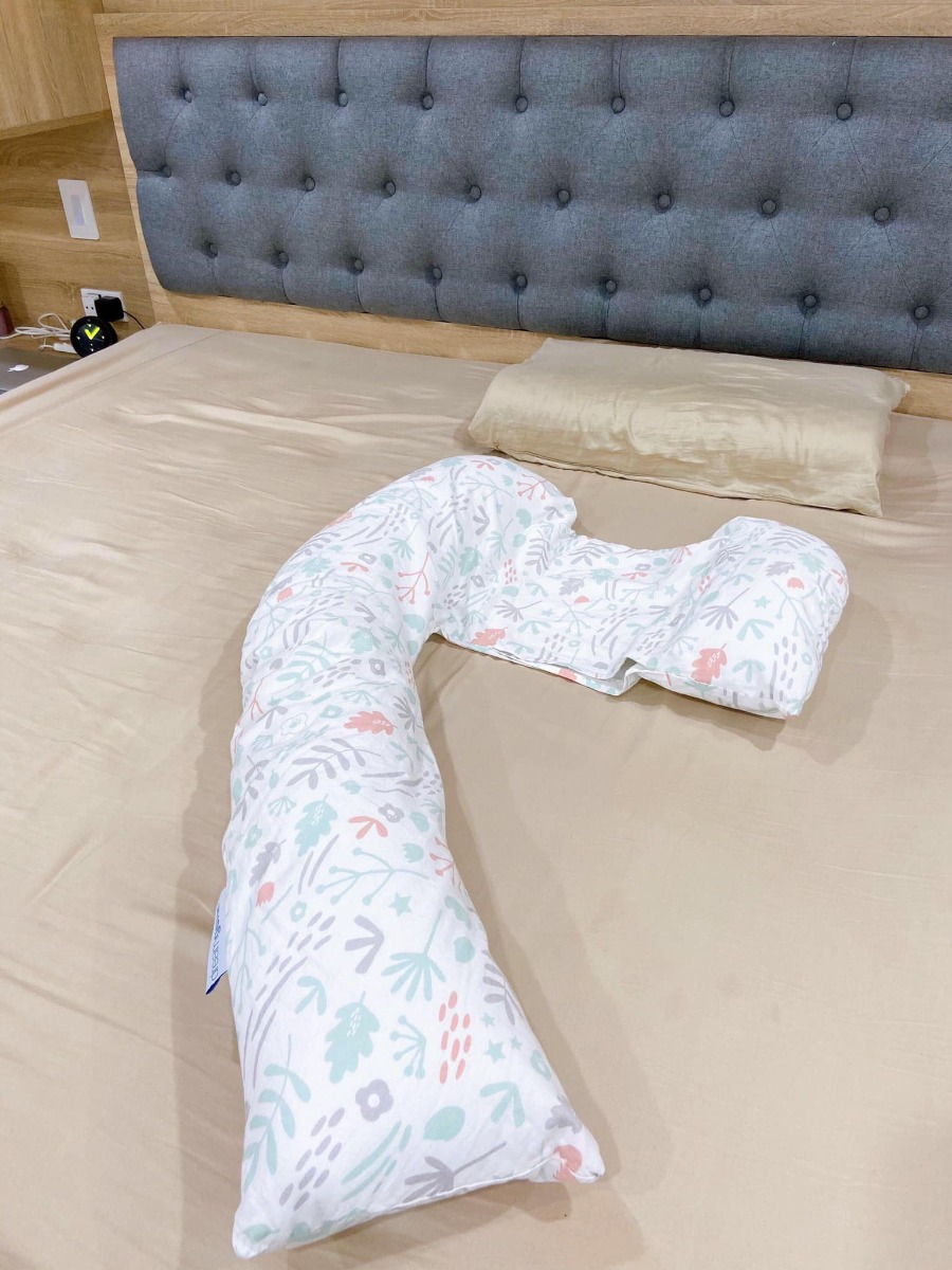 Đẻ đến bạn thứ 4 rồi mà mãi đến lần chót chốt sổ này mới phát hiện ra bao nhiêu thứ hay ho dành cho mẹ bầu lẫn cho con bú, có những món đồ dùng vừa đa năng, vừa hiệu quả mà mình ước gì có thể biết sớm hơn!

Hôm trước mình chia sẻ cái cốc hứng sữa kiêm hút sữa, chắc nhiều bạn sau đó đã được “kiểm nghiệm” độ vi diệu rồi đúng ko? Hôm nay mình “khoe” thêm cái gối này!

Đây là chiếc gối bầu đa năng DREAMGENII, được “khai sinh” ở Anh, và sản xuất tại Thổ Nhĩ Kỳ. Nhìn thì đơn giản thế thôi, nhưng có sử dụng mới thấy từ thiết kế tới chất liệu, đường may… đều cực kỳ lợi hại, và nó hoàn toàn có lí do để có giá bán cao gấp 6-7 lần các loại gối bầu đang bán phổ biến hiện giờ.

- Khi bầu thì dùng để điều chỉnh tư thế ngủ, nâng đỡ toàn bộ cơ thể, giúp mẹ bầu có tư thế ngủ đúng, giấc ngủ ngon và sâu hơn. Đặc biệt là những tháng cuối thai kỳ, bụng to, chèn ép nhiều, mình không thể nằm ngủ nổi mà không có cái gối này luôn!

- Tùy từng vị trí nâng đỡ cơ thể của mình mà gối có độ mềm khác nhau chứ không nhồi bự bông, dày sụ và cứng ngắc như loại gối bầu chữ U mình từng dùng qua. Gối DREAMGENII này vừa nhẹ vừa mềm, gọn gàng nữa chứ không nặng chịch hay cồng kềnh. Chính vì thiết kế về hình dạng và chất liệu bông nhồi (100% bông Thổ Nhĩ Kỳ) nên khi hỗ trợ mẹ bầu rất tốt, giảm đau nhức, chuột rút và đau vùng xương chậu.

- Tới giai đoạn sau sinh, gối này cũng thay thế luôn gối chữ C, giúp nâng đỡ phần hông của mẹ và toàn bộ cơ thể của em bé khi mẹ ngồi cho con bú. Mình cũng từng dùng qua gối chữ C rồi, và với mình thì cái gối DREAMGENII này còn lợi hại hơn gối chữ C vì có thêm phần nâng đỡ đầu của bé, giúp mẹ có thể rảnh tay, không cần tới 1 tay đỡ phần đầu của con mà đầu vẫn luôn ở vị trí cao hơn dạ dày, đảm bảo tu ti thoải mái và không lo bị sặc sữa/nôn trớ! Mình lại chủ yếu là ngồi cho bú để con bú xong là mẹ cũng ngồi luôn đó vỗ ợ cho con luôn, nên lại càng thấy cái gối này siêu tiện!

- Vỏ gối được làm bằng chất liệu cotton tự nhiên 100%, rất mịn và thoáng, mình đã trải qua cả mùa hè ôm bụng bầu nằm ngủ với cái gối này và luôn có cảm giác mát mẻ khi ôm gối. Vỏ cũng dễ dàng tháo ra để giặt nhé.

- Gối bầu DREAMGENII cũng là sản phẩm được Bộ Y tế của Anh cấp chứng nhận là dụng cụ y khoa, và được sử dụng trong bệnh viện phụ sản ở Anh đấy!